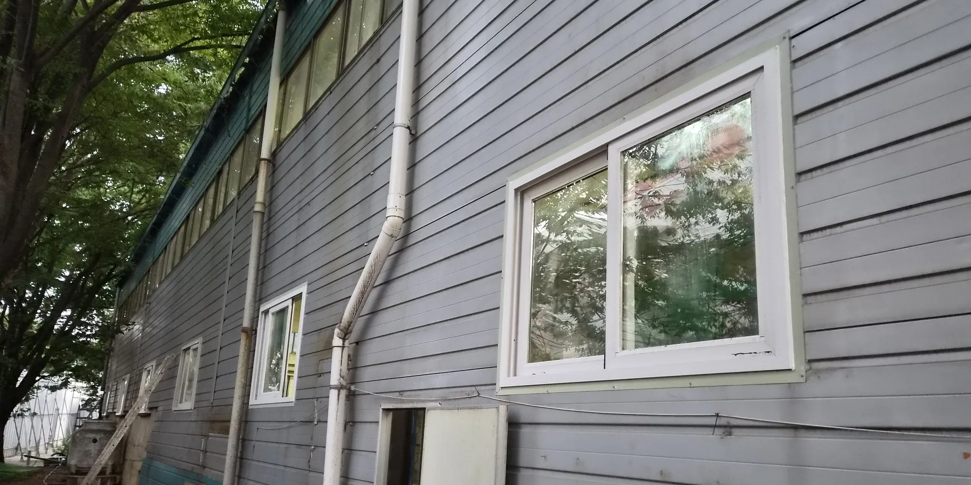 회색 판넬 외벽에 새시 창호가 설치된 창고 건물 측면 전경